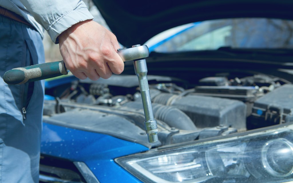 Mecânico apertando peça no motor durante a revisão
